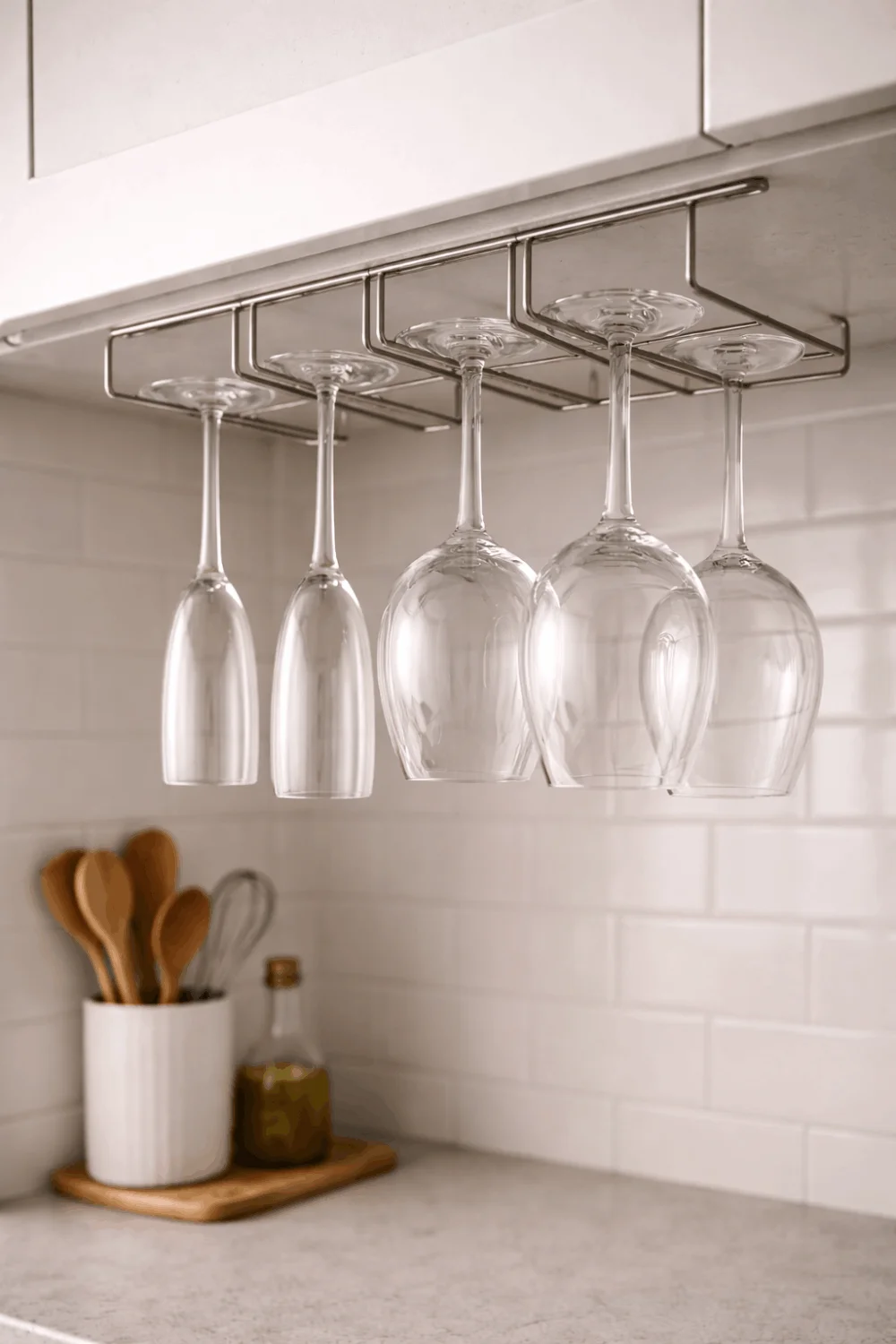 Elegant stemware hanging neatly in an under-cabinet rack, optimizing vertical storage in a small apartment kitchen.